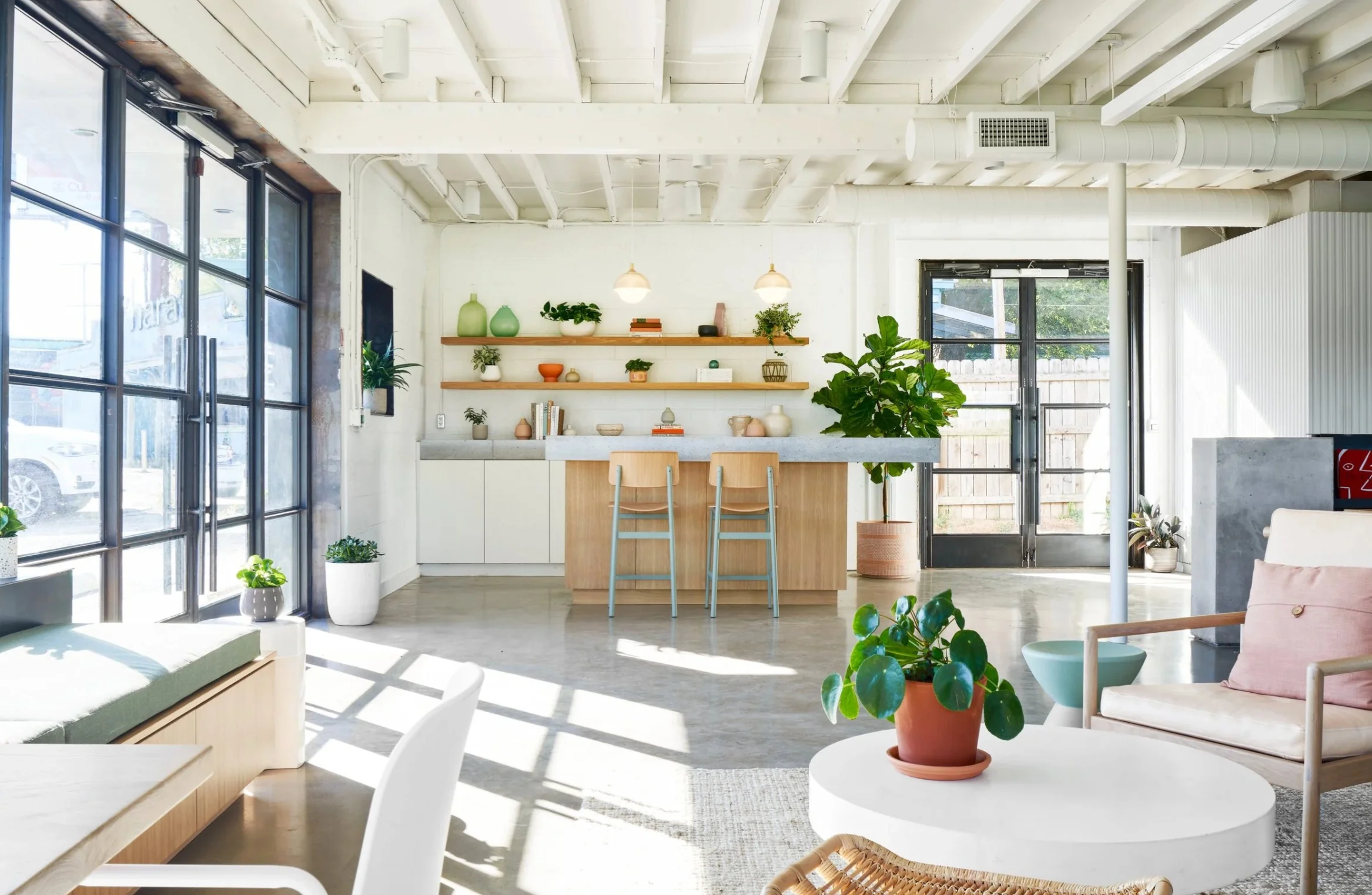The Commune coworking space in North Loop with bright industrial interior, plants, wooden shelving, and bar seating