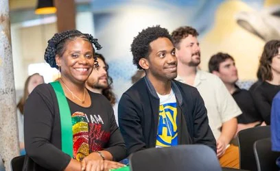 High Voltage community event with smiling audience members seated in rows at an Uptown New Orleans creative hub