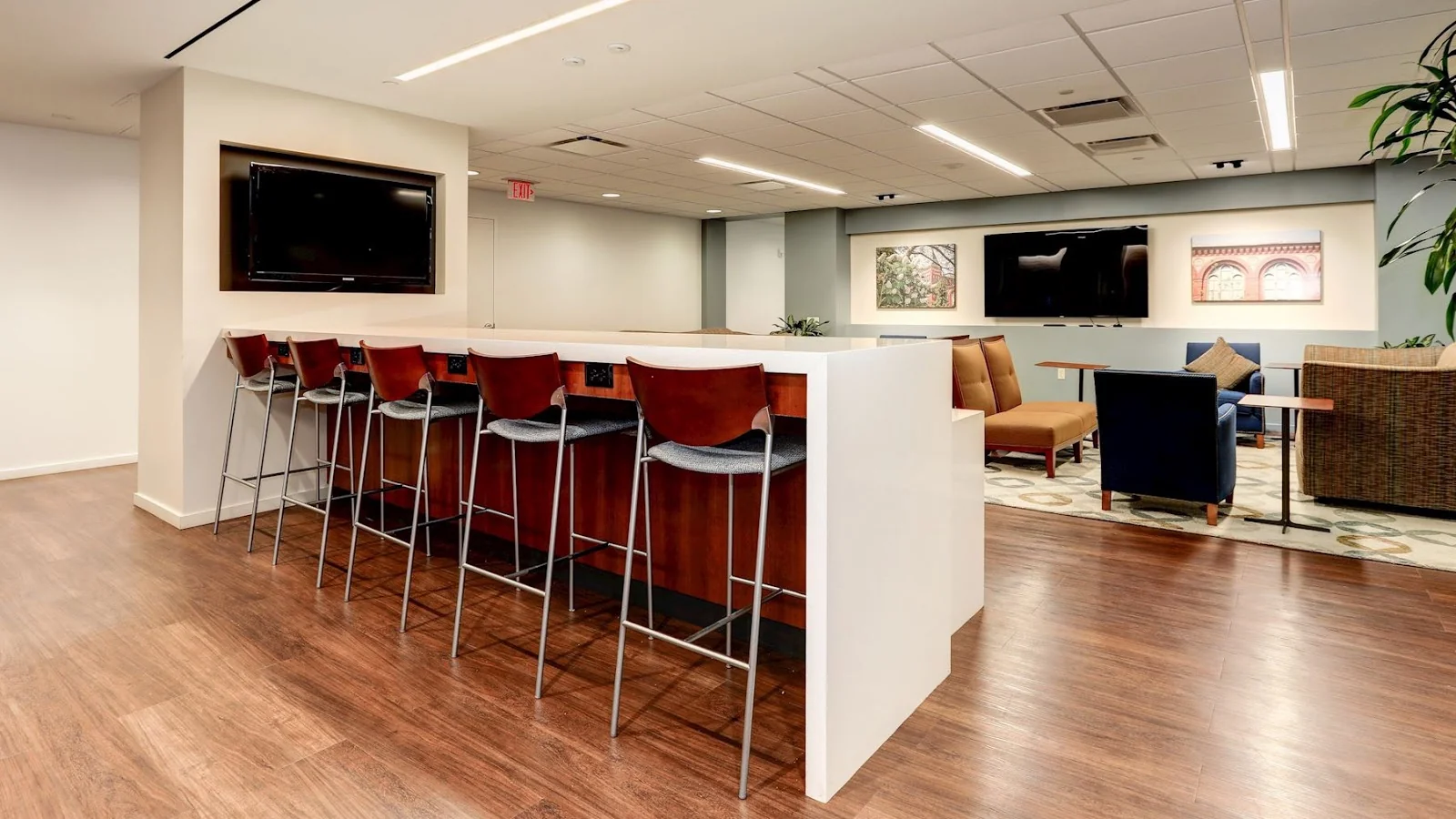 Carr Workplaces Penn Ave lounge with cherry wood bar stools, TV area and patterned rug