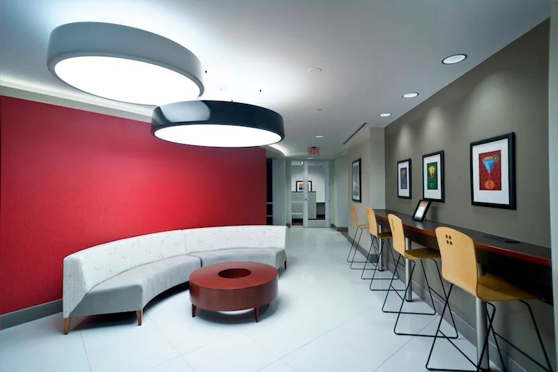 Metro Offices Farragut West with red accent wall, curved white sofa, round coffee table and bar seating