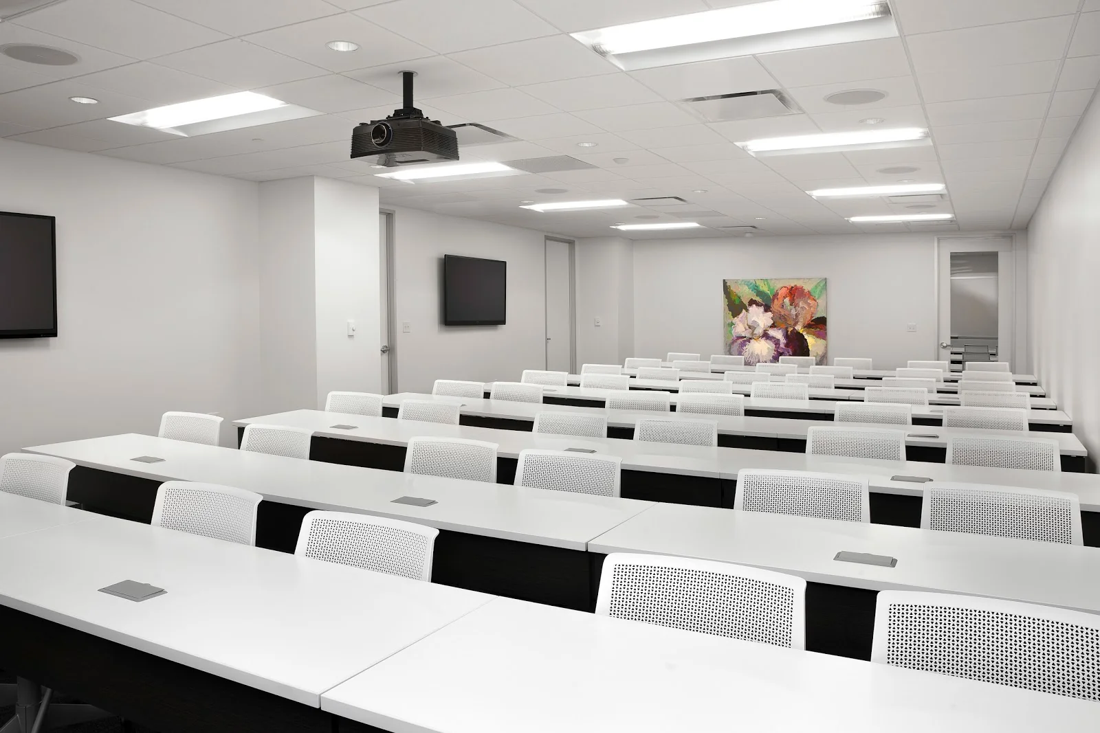 AdvantEdge Workspaces Thomas Jefferson training room with rows of white desks, projector, and floral painting