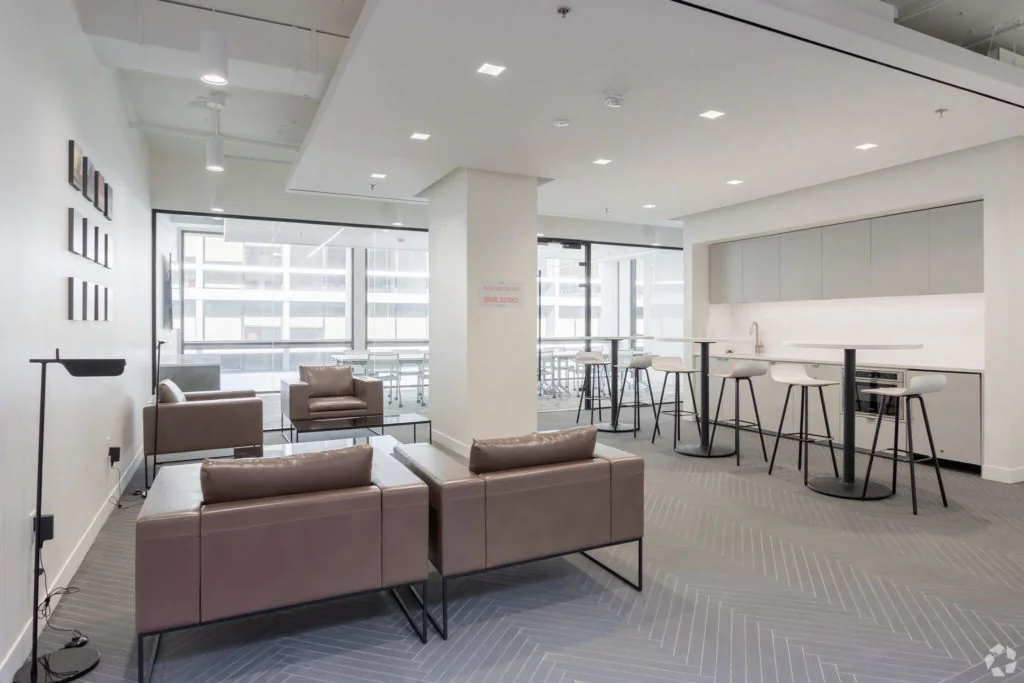 Symbiosis modern lounge with mauve leather sofas, herringbone gray flooring, white kitchen bar area, and city views