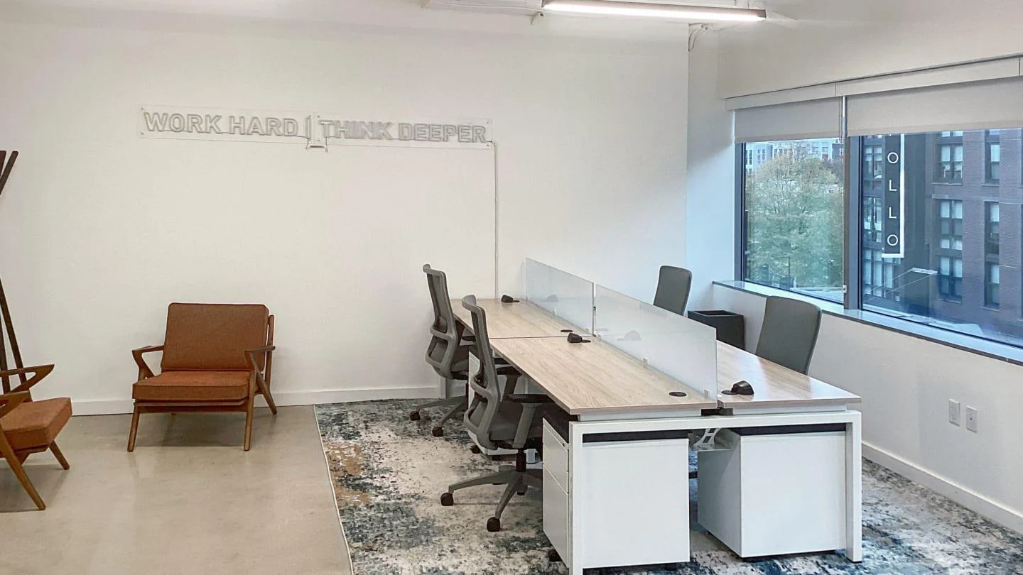 Spaces H Street minimalist private office with Work Hard Think Deeper wall art, shared desks with privacy screens, and mid-century accent chair