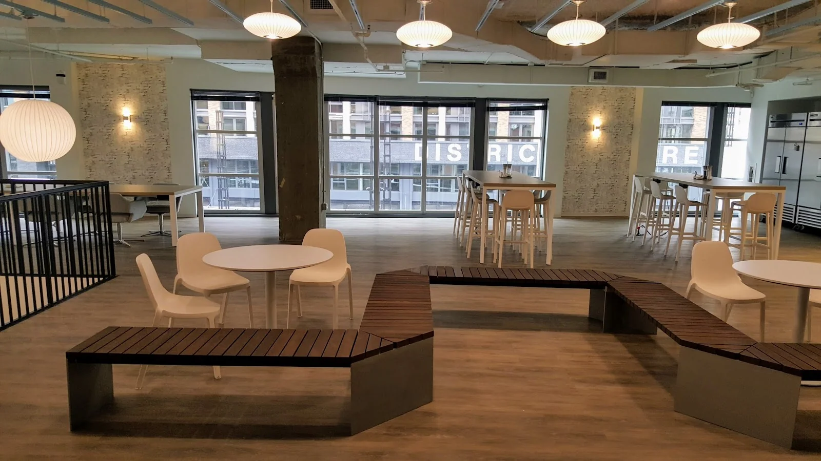 Spaces The Wharf open area with white furniture, wooden benches, globe pendant lights and industrial ceiling